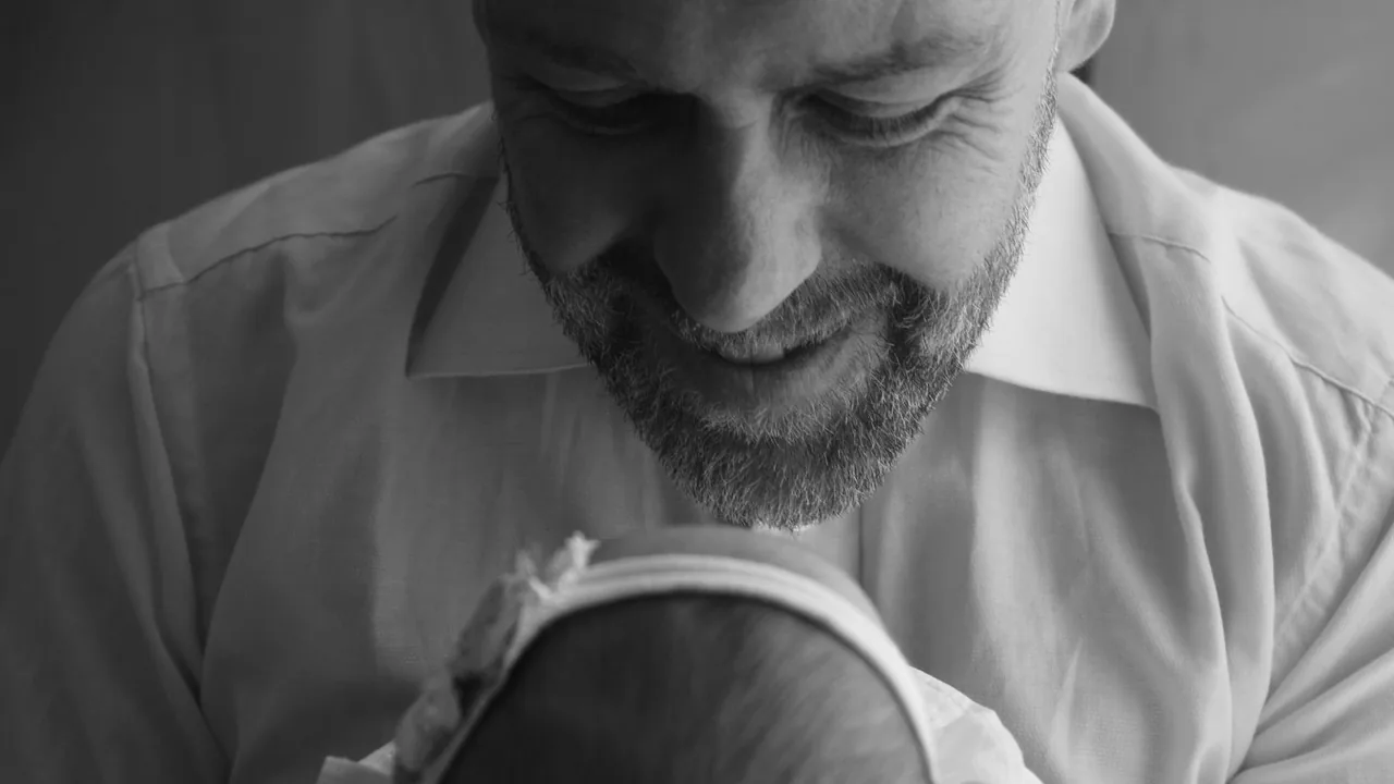 Pai olha para bebê recém-nascido no colo