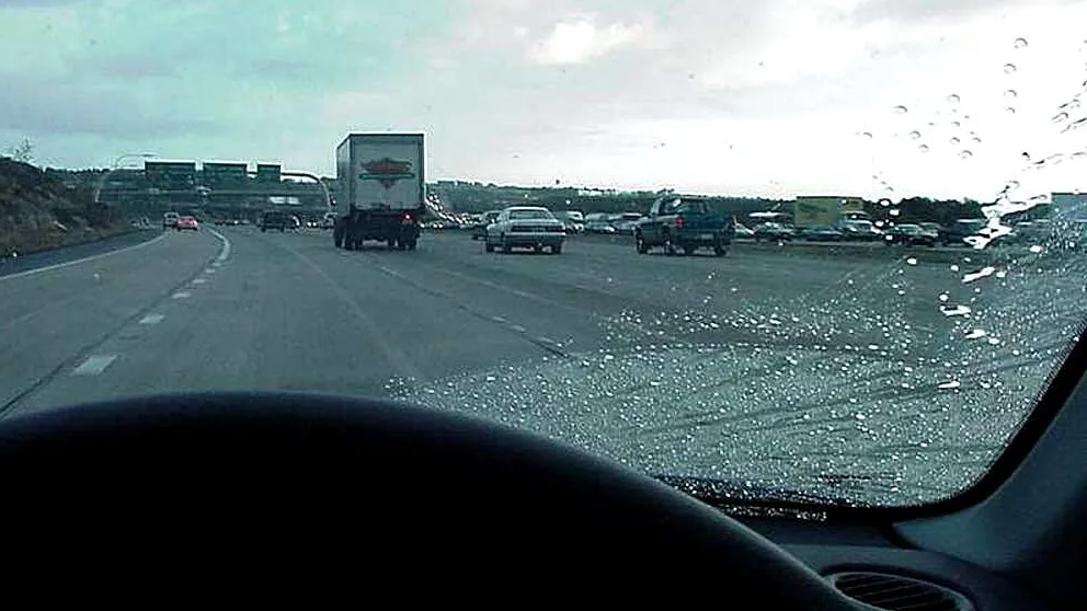 Trânsito em uma rodovia visto através do para-brisa em dia de chuva, para ilustrar riscos cobertos pelo seguro auto